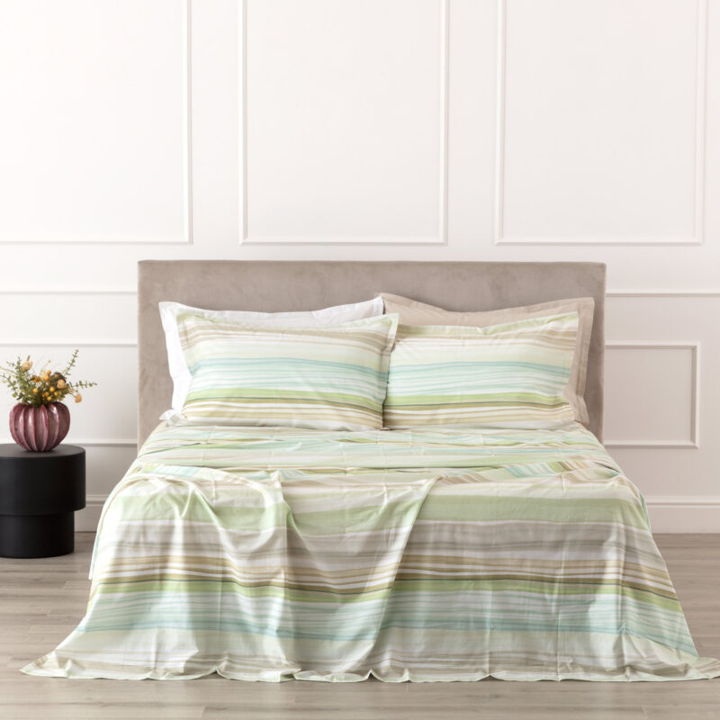 COMPLETO LENZUOLO COPRILETTO PERCALLE LUSHANA COMPLETO LENZUOLO COPRILETTO PERCALLE LUSHANA Illenzuolo copriletto Lushana in percalle reinterpreta il motivo a righe in chiave contemporanea, con una stampa digitale su percalle 100% cotone che crea un effetto visivo morbido e armonioso. Le sfumature cromatiche scorrono leggere sul tessuto, portando movimento alla zona notte senza appesantire l’ambiente. Il sotto e il retro delle federe in tinta unita completano il design con equilibrio, mentre la mano fresca e compatta del percalle assicura comfort e traspirabilità. Proposta nelle tonalità Cannella, Ostrica, Orchidea e Salvia a seconda della misura, Lushana si inserisce con naturalezza in interni moderni, nordici o soft minimal. Cannella scalda l’ambiente, Ostrica illumina con discrezione, Salvia richiama palette naturali, mentre Orchidea aggiunge un accento più decorativo. Una parure pensata per chi cerca qualità tessile, stile contemporaneo e una sensazione di comfort quotidiano. Qualità/Materiali: 100% Percalle di Cotone Dimensione 1 Piazza e Mezza: 180x290 cm - con balza applicata - 1 federa Federe: cm 50x80 - 4 volants